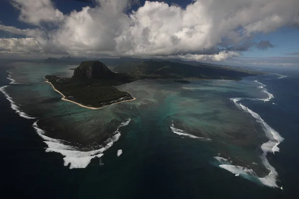 Остров омывается со всех сторон океаном и над которым собралось много облаков — стоковое фото