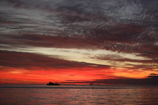 Puesta de sol en el océano que colorea el agua y el cielo en color rojo —  Fotos de Stock