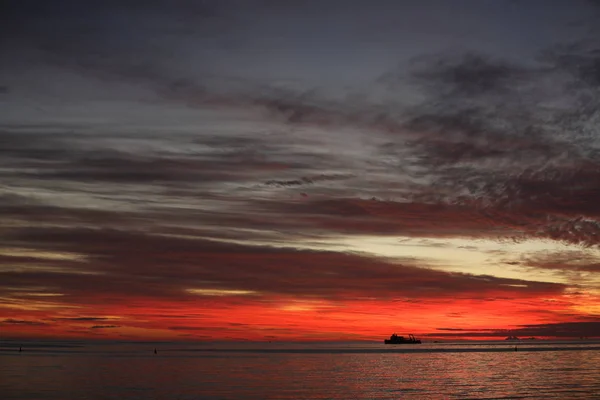 Puesta de sol en el océano que colorea el agua y el cielo en color rojo —  Fotos de Stock