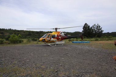 Reunion Mayıs 5, 2018: Sarı kırmızı helikopter etrafında birçok ağaç olan bir alanda duruyor.