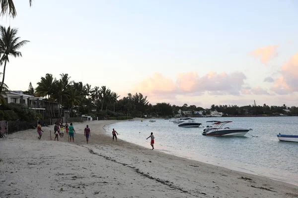 Reunión mayo 5, 2018: Puesta de sol en la playa de la isla de Mauricio, donde los yates flotan en el agua y la gente juega en la playa — Foto de Stock