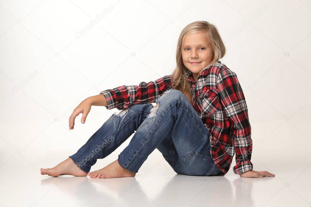 Cute girl sitting on the floor and smiling sincerely. White background