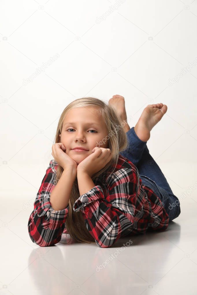 Girl with long blond hair is lying on the floor. White background