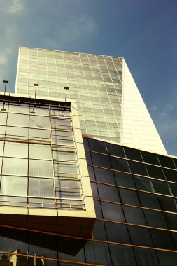 Parlak güneşli bir günde bir gökdelen mavi gökyüzünde güneş ışınları ile cam cephe. Modern binalar, iş bölgesinde şehir. Ekonomi, finans, iş kavramı. Alttan üste göster.