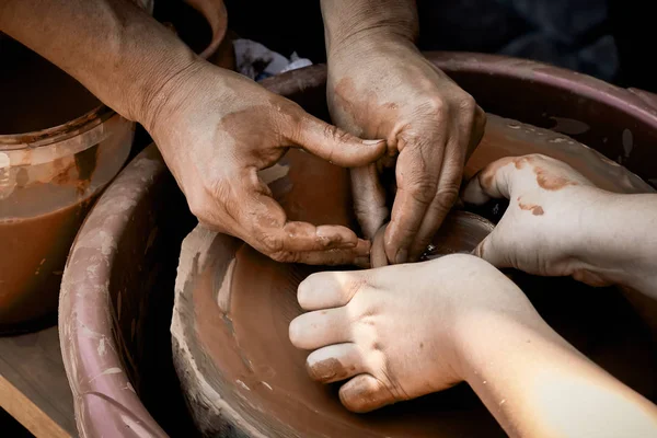 Pottery training. The hands of the pupil and master over the potter. The concept of transferring knowledge and skills to generations.