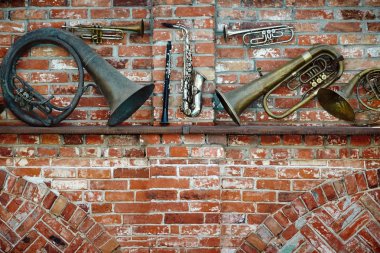 Set of old brass musical instruments on a red brick wall background in grunge style. clipart