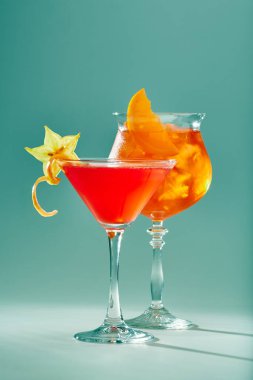 Gözlüklü bir bacak üzerinde buz ile bir açık yeşil renkli meyve ile kırmızı renkteki iki egzotik kokteyller.