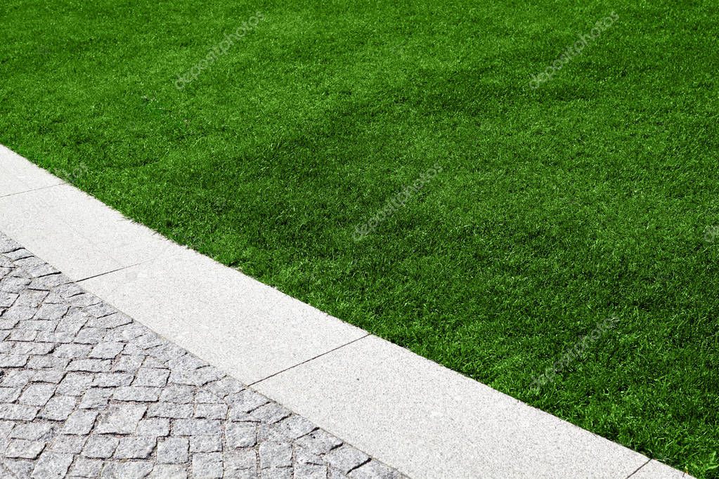 A beautiful lawn with green grass and a path decorated with granite stones.
