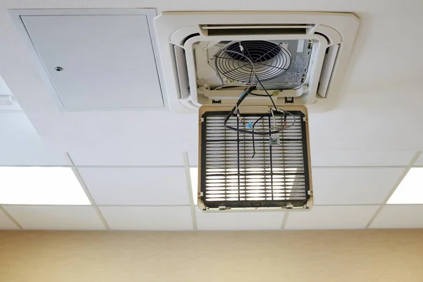 An industrial air conditioner hanging on a ceiling tank in the room. Repair and prevention of office and industrial cooling systems.