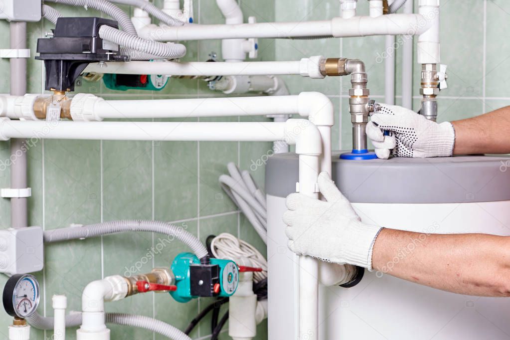 Engineer controlling the heating pipes at the boiler room. Plumber doing maintenance jobs for water and heating systems