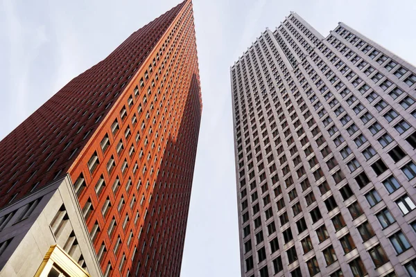 Two high-rise buildings, red and gray. Modern business offices and blue sky in the background.