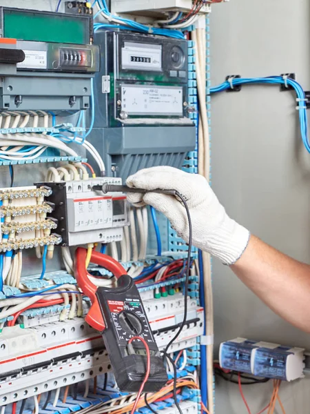 Elinde elektrik panel yanında duran bir tanı aracı ile üst düzey elektrikçi elektrik devreleri performansını ölçer.