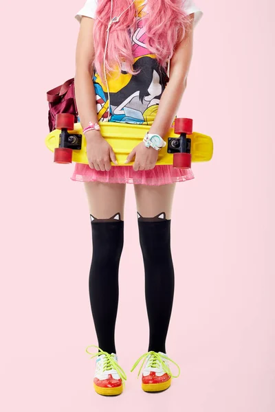 一个女孩的肖像在 Kawaii 风格的丝袜与滑板和背包 在粉红色的背景 — 图库照片