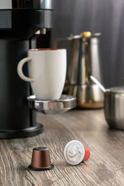 Capsules for making coffee in a coffee machine lie on the table against the background of a home kitchen. Selective focus. Vertical image.