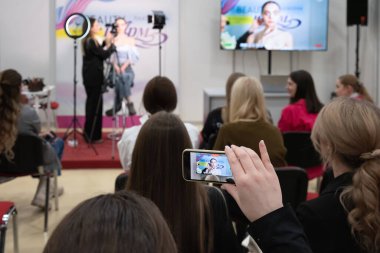 Ziyaretçiler akıllı telefondan video kaydediyor. Antrenör yeni makyaj teknikleri öğretiyor. Güzellik endüstrisi sergisi 