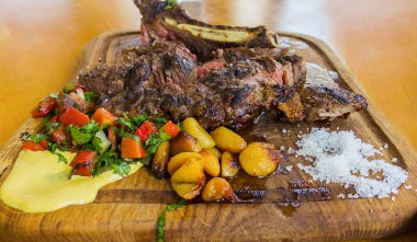 Sığır biftek salata ve sos ile ahşap bir tahta üzerinde servis