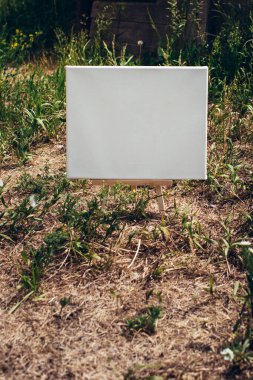 Yeşil yapraklar üzerinde beyaz boş maket şablonu poster resmi