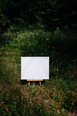 Yeşil yapraklar üzerinde beyaz boş maket şablonu poster resmi