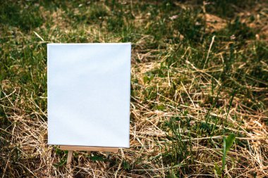 Yeşil yapraklar üzerinde beyaz boş maket şablonu poster resmi