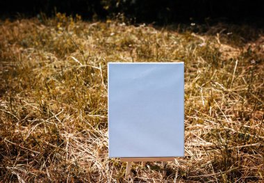 Yeşil yapraklar üzerinde beyaz boş maket şablonu poster resmi