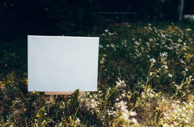 Yeşil yapraklar üzerinde beyaz boş maket şablonu poster resmi