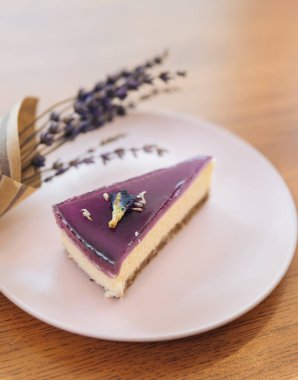 Tahta arka planda lavantalı bir dilim diyet peynirli kek.