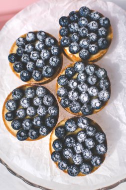 Limon kremalı ve karamelli kum sepeti. Taze yaban mersini ve pudra şekeriyle süslenmiş..