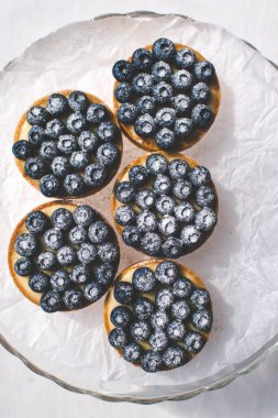 Limon kremalı ve karamelli kum sepeti. Taze yaban mersini ve pudra şekeriyle süslenmiş..