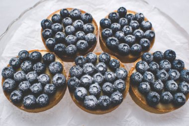 Limon kremalı ve karamelli kum sepeti. Taze yaban mersini ve pudra şekeriyle süslenmiş..