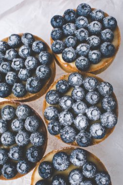 Limon kremalı ve karamelli kum sepeti. Taze yaban mersini ve pudra şekeriyle süslenmiş..