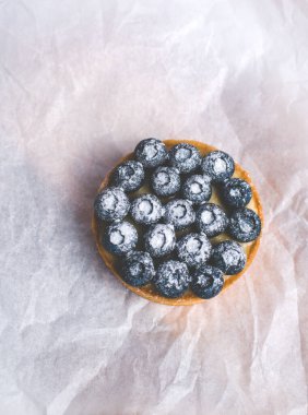 Limon kremalı ve karamelli kum sepeti. Taze yaban mersini ve pudra şekeriyle süslenmiş..