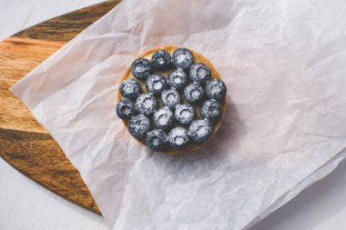 Limon kremalı ve karamelli kum sepeti. Taze yaban mersini ve pudra şekeriyle süslenmiş..