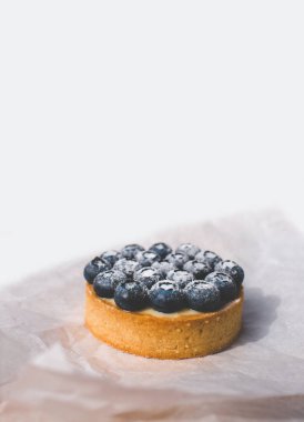 Limon kremalı ve karamelli kum sepeti. Taze yaban mersini ve pudra şekeriyle süslenmiş..