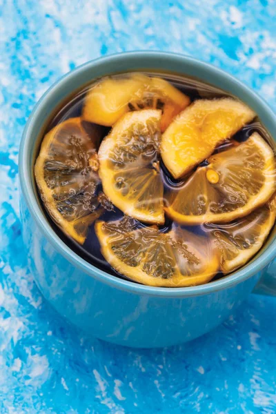 A large blue mug with tea and some lemon slice