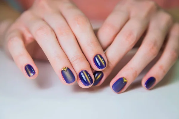 Finished purple shellac manicure, woman in nail beauty salon.