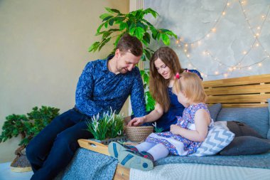 Mutlu genç ebeveynler ve küçük kızları evde birlikte oynuyorlar. Aile, çocukluk ve eğlence kavramı