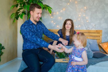 Mutlu genç ebeveynler ve küçük kızları birlikte oynuyorlar.