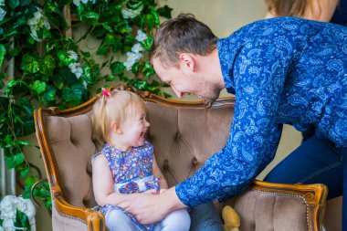 Mutlu genç ebeveynler ve küçük kızları birlikte oynuyorlar.