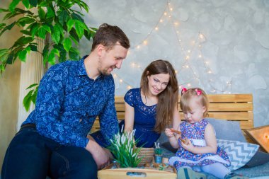 Mutlu genç ebeveynler ve küçük kızları birlikte oynuyorlar.