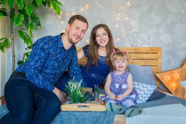 Mutlu genç ebeveynler ve küçük kızları birlikte oynuyorlar.