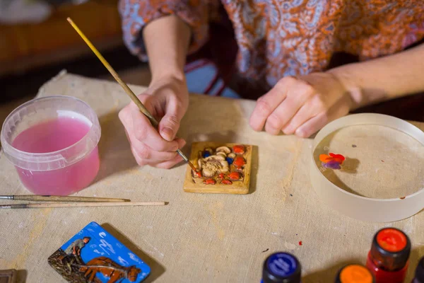 Professional woman potter painting ceramic souvenir magnet in potter — Stock Photo, Image