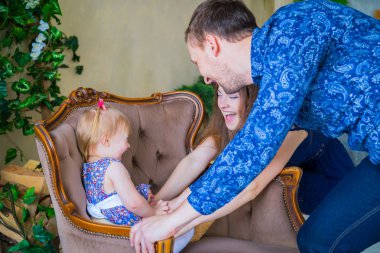 Mutlu genç ebeveynler ve küçük kızları birlikte oynuyorlar.