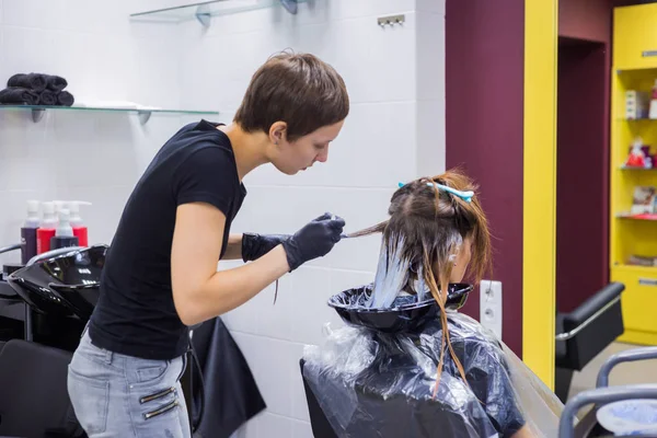 Cabeleireiro profissional colorir o cabelo da mulher cliente no estúdio — Fotografia de Stock