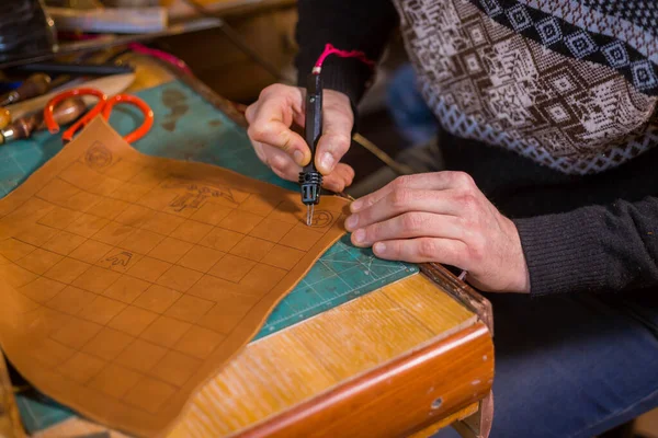 Skinner making decorative details on leather playing field