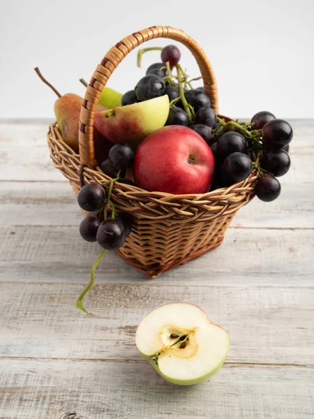 basket with fruit plum, grapes, apple, pear. put on a wooden board