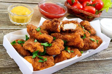 Tavuk kanadı. Ahşap bir masa üzerinde farklı soslar kızarmış gevrek et parçaları. Geleneksel snack.