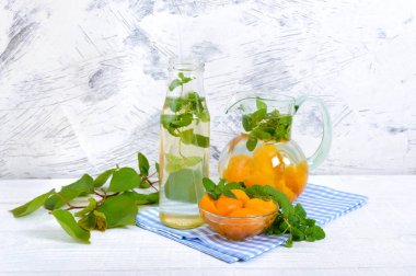 Yaz soğuk içecekler. Delicious içecek kayısı ve nane Beyaz ahşap zemin üzerine gözlük ile yenileniyor. Meyve kompostosu.