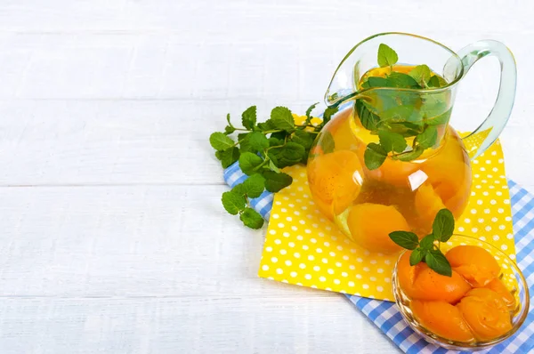 Summer cold drinks. Delicious refreshing drink with apricot and mint in glasses on a white wooden background. Compote of fruits.