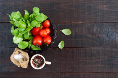 Sağlıklı bir diyet için ahşap bir zemin üzerine Yeşil taze yaprakları organik fesleğen ve küçük olgun domates ve biber. Üstten görünüm. Projeniz için boş alan.