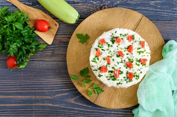 A delicious cake of zucchini, tomatoes and cheese on a wooden table. Top view. Vegetable cake.